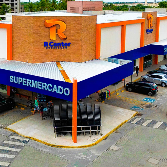 Vista aérea da loja R Center Messejana, com fachada laranja e azul e estacionamento